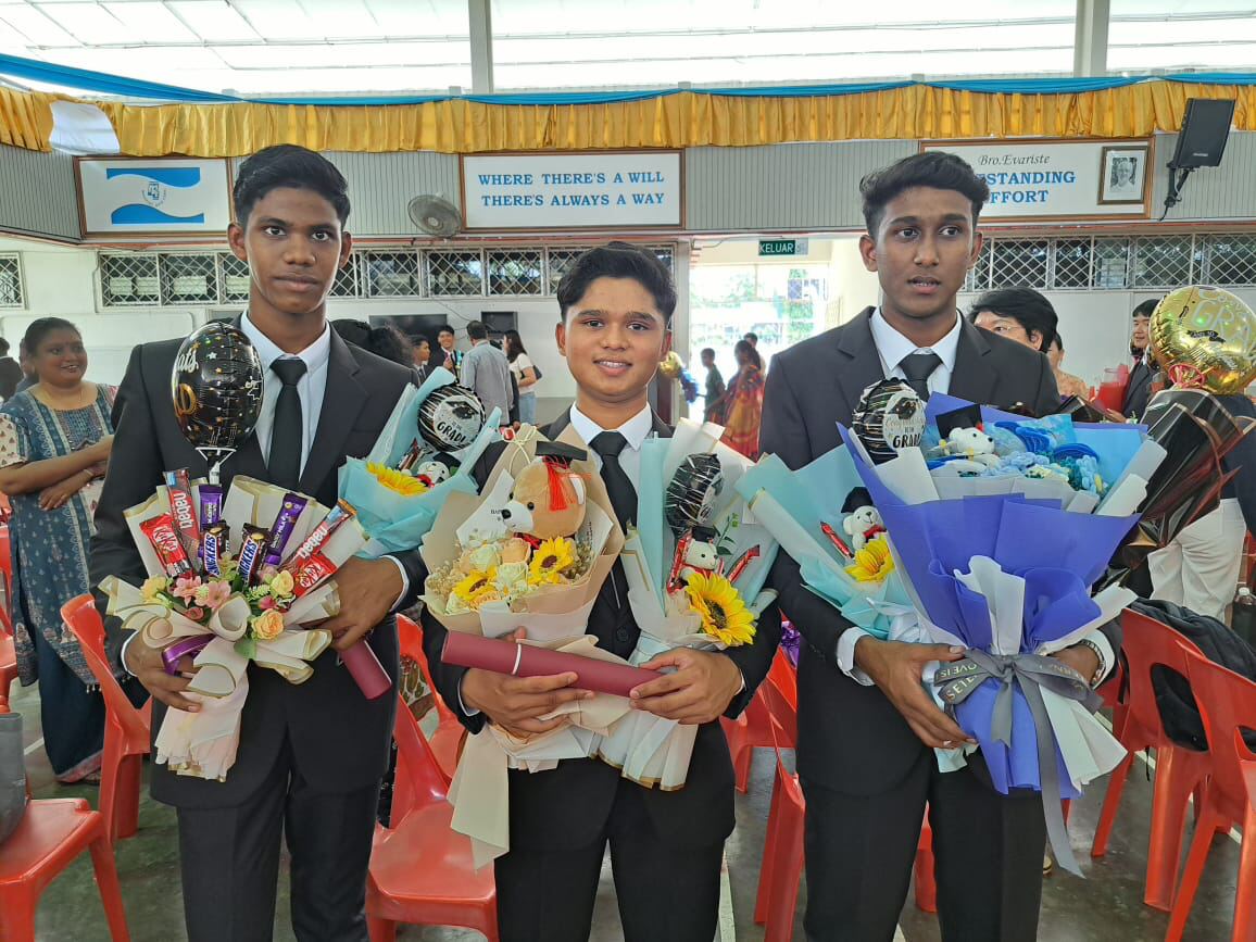 Three young men celebrating their graduation with bouquets