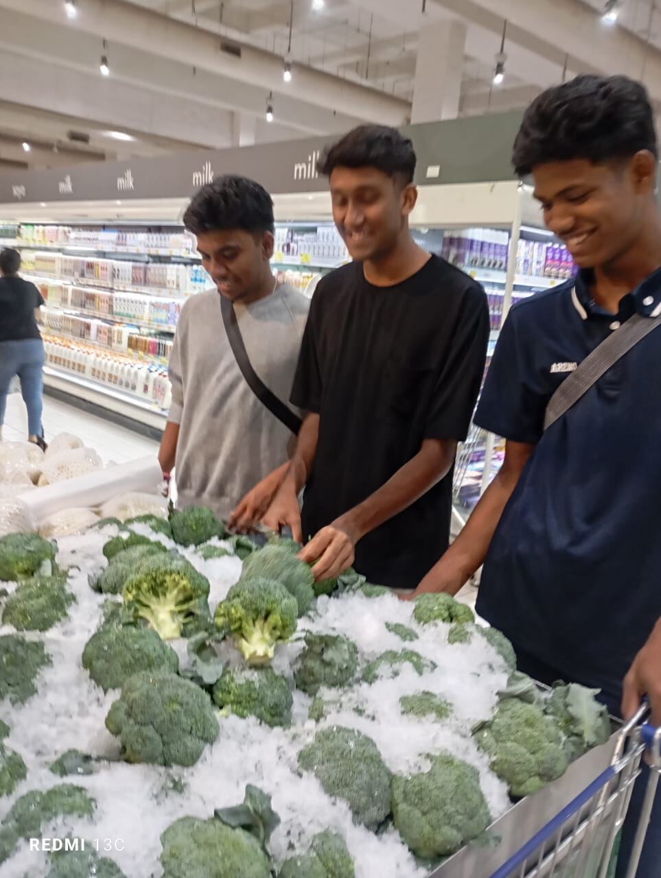 Young men picking out broccoli at the supermarket